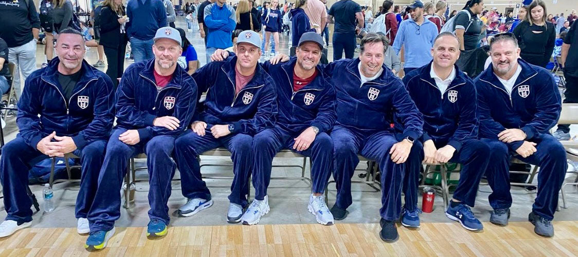 Group of men in matching blue tracksuits sitting on a bench outdoors.  Sweatsedo, navy blue, admiral,  personalize, embroidery